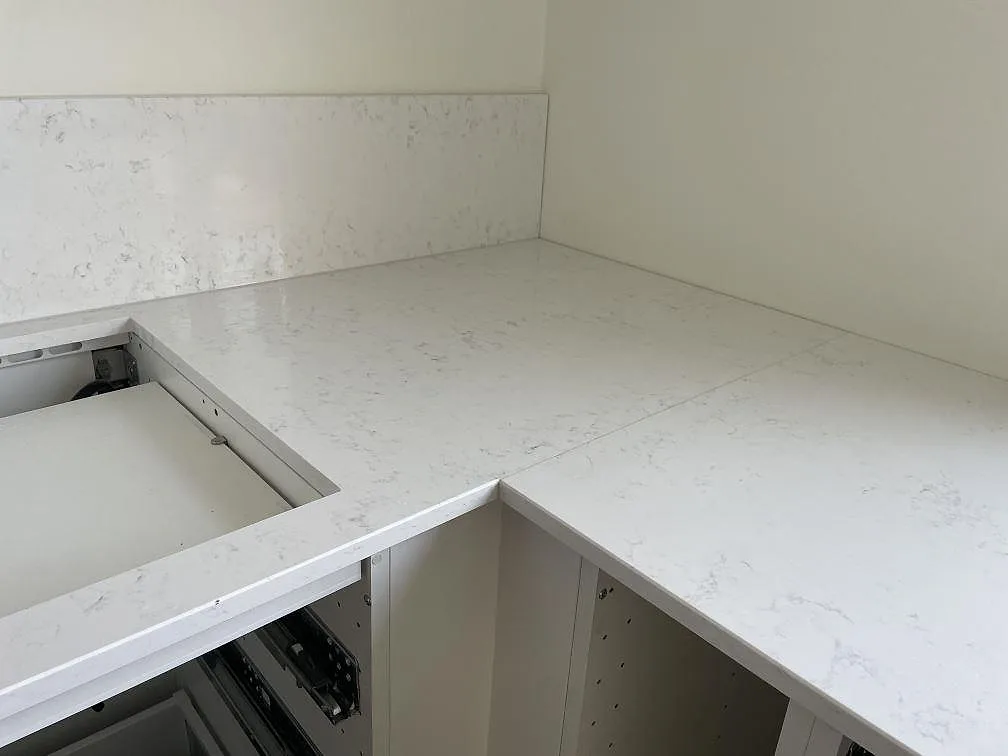 Närbild av köksbänkskiva i polerad Quarella Navona med ljus ådring, låg stänkkant och öppen stomme i Malmö.