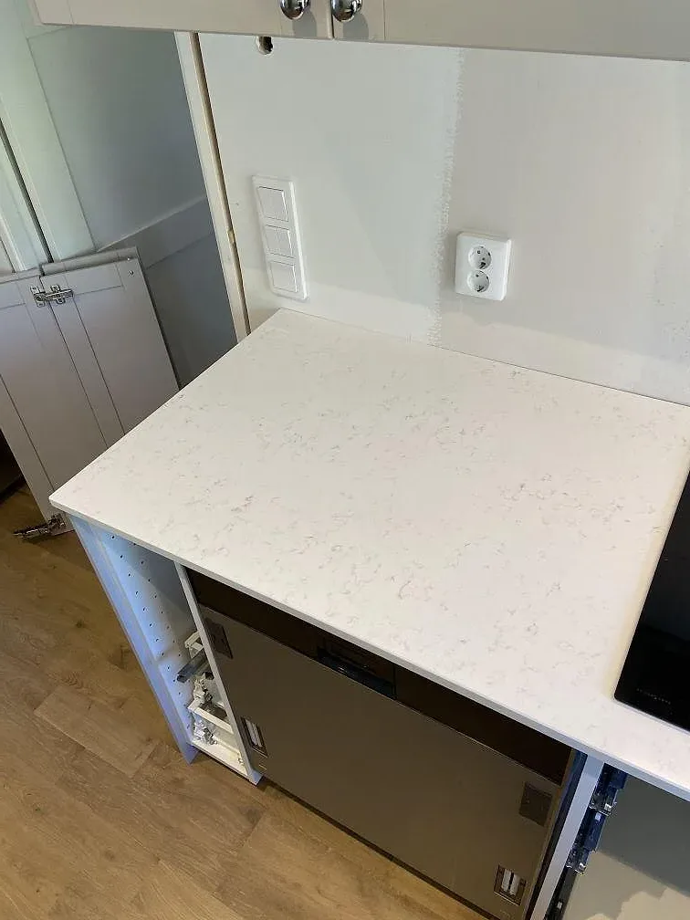 Detalj av ljus Quarella Navona köksbänkskiva med induktionshäll och stänkkant i ett kök i Skanör.