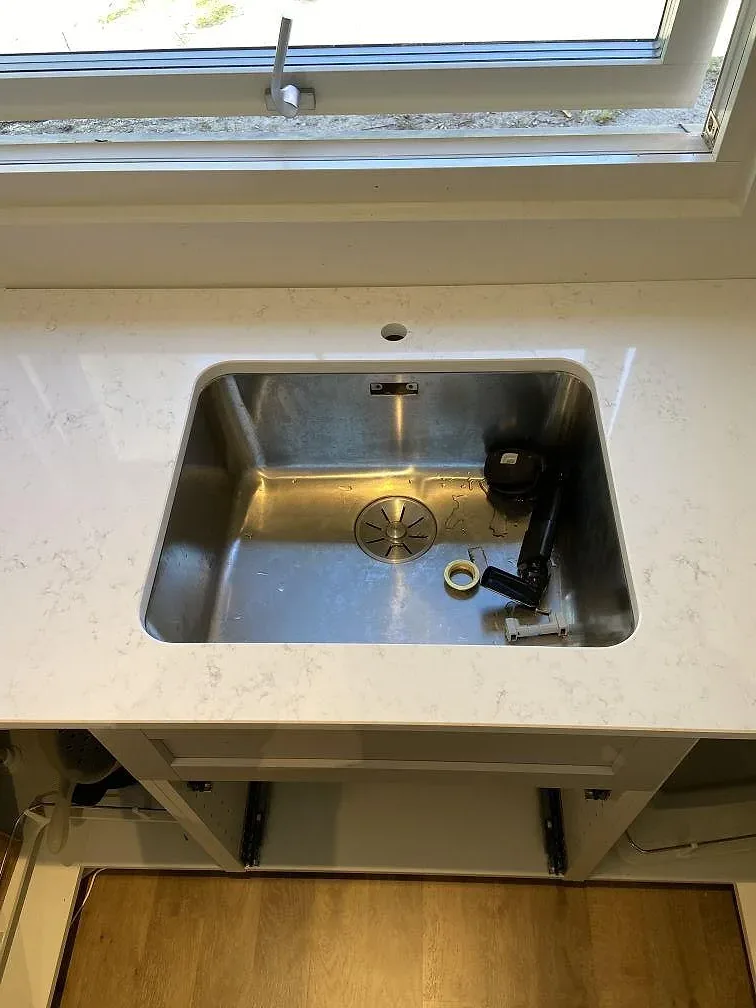 Underlimmad rostfri diskho i ljus Quarella Navona köksbänkskiva med grå ådring i ett kök i Skanör.