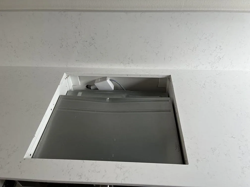 Polerad köksbänkskiva i vit Quarella Navona med urtag för häll, sedd uppifrån i ett kök i Skurup.