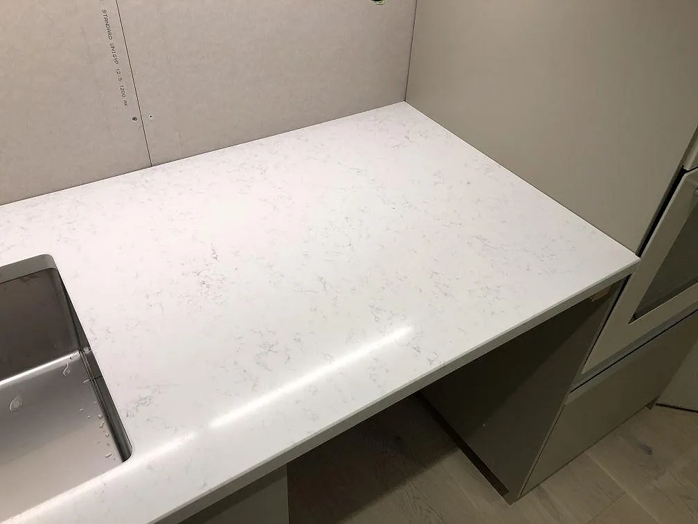 Underlimmad rostfri diskho i en köksbänkskiva av Quarella Navona kvartskomposit i ett kök i Ystad.