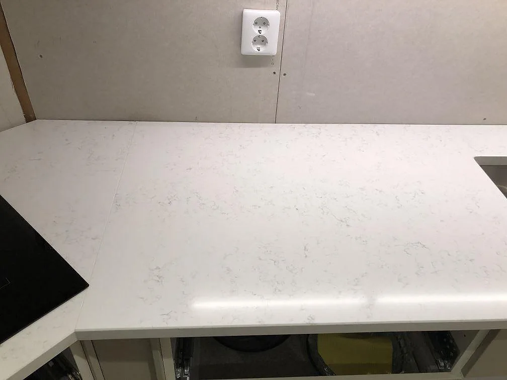 Polerad köksbänkskiva i Quarella Navona med plats för induktionshäll i ett kök i Ystad.