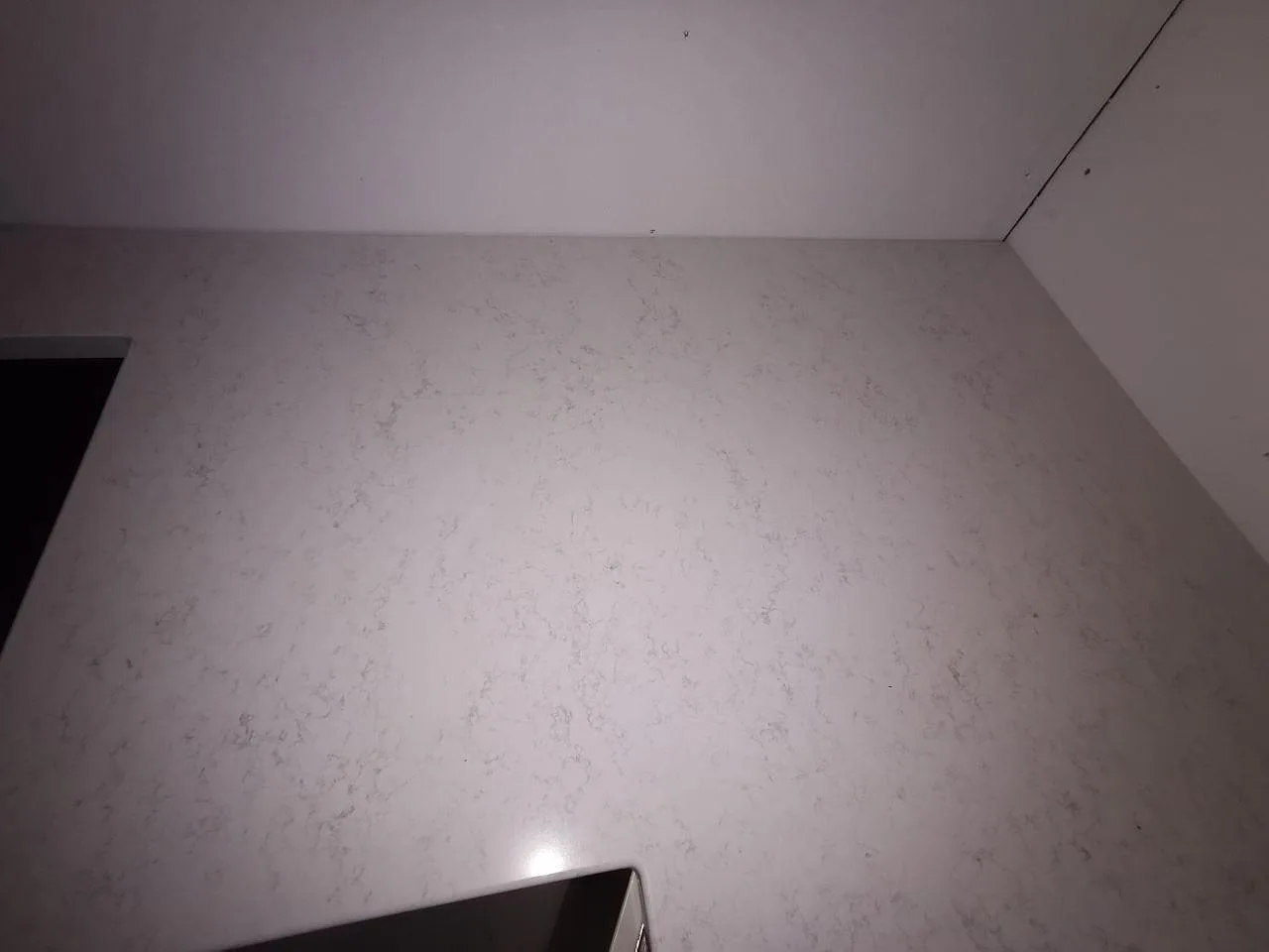 Underlimmad svart diskho infälld i polerad Quarella Palatino bänkskiva i ett kök i Åkarp.