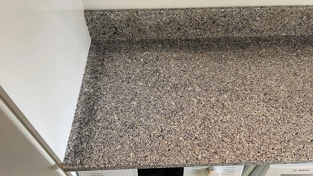 Ytbild av polerad Rosa Beta granit på installerad tvättbänk med uppvikt stänkkant i Hyllinge.