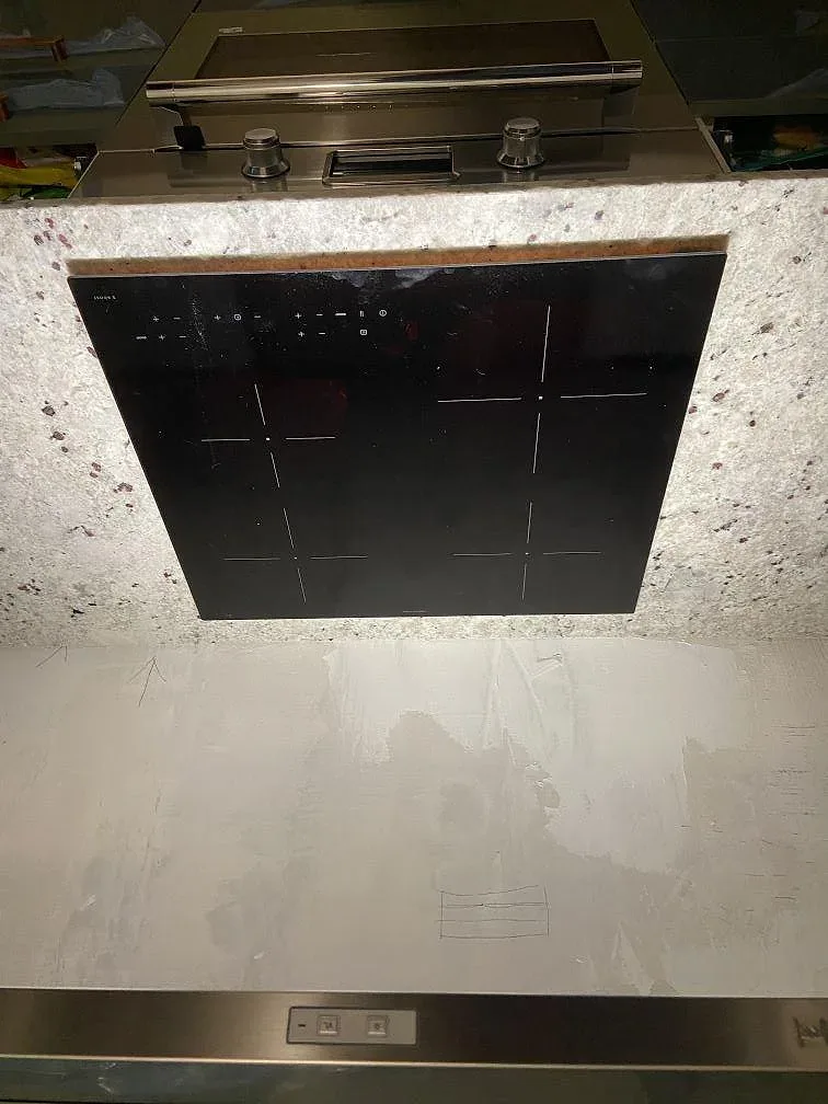 Övermonterad induktionshäll på polerad bänkskiva i Sensa Colonial White granit i ett kök i Malmö.
