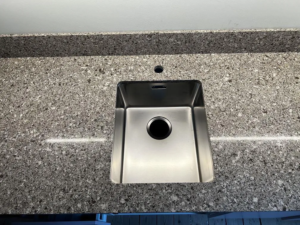 Underlimmad rostfri diskho och kranhål i polerad Silestone Alpina White, med 12 mm stänkkant i ett kök i Göteborg.