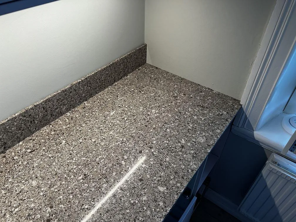 Hörn på köksbänkskiva i polerad Silestone Alpina White med uppvikt stänkkant vid fönster i Göteborg.