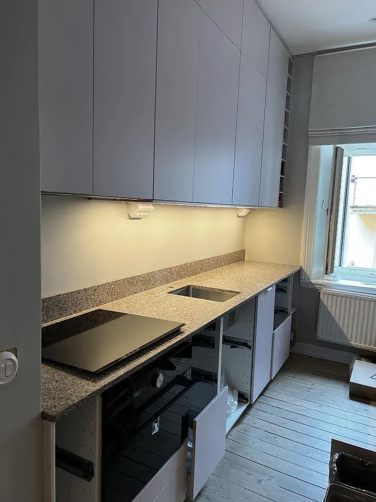 L-formad köksbänkskiva i polerad Silestone Alpina White, 20 mm komposit, med svart induktionshäll och rostfri diskho i Göteborg.