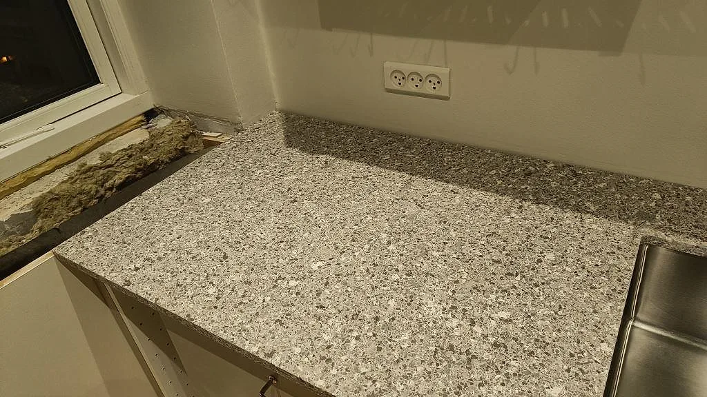 Köksbänkskiva i Silestone Alpina White med uppvikt stänkkant och diskho i ett kök under montering i København S.