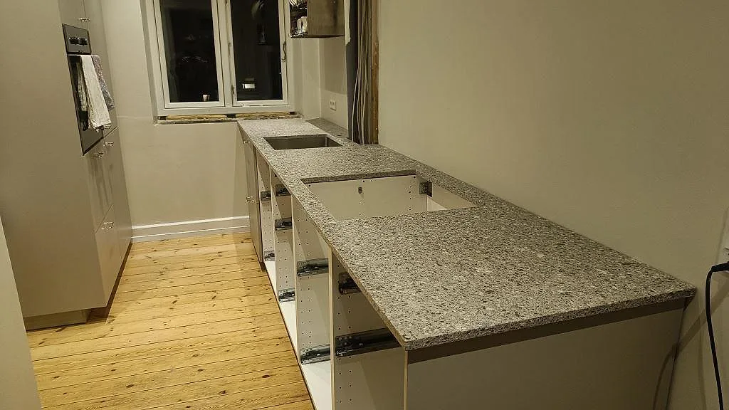 Lång köksbänkskiva i Silestone Alpina White komposit, matt Mocka, monterad i ett smalt kök i København S.