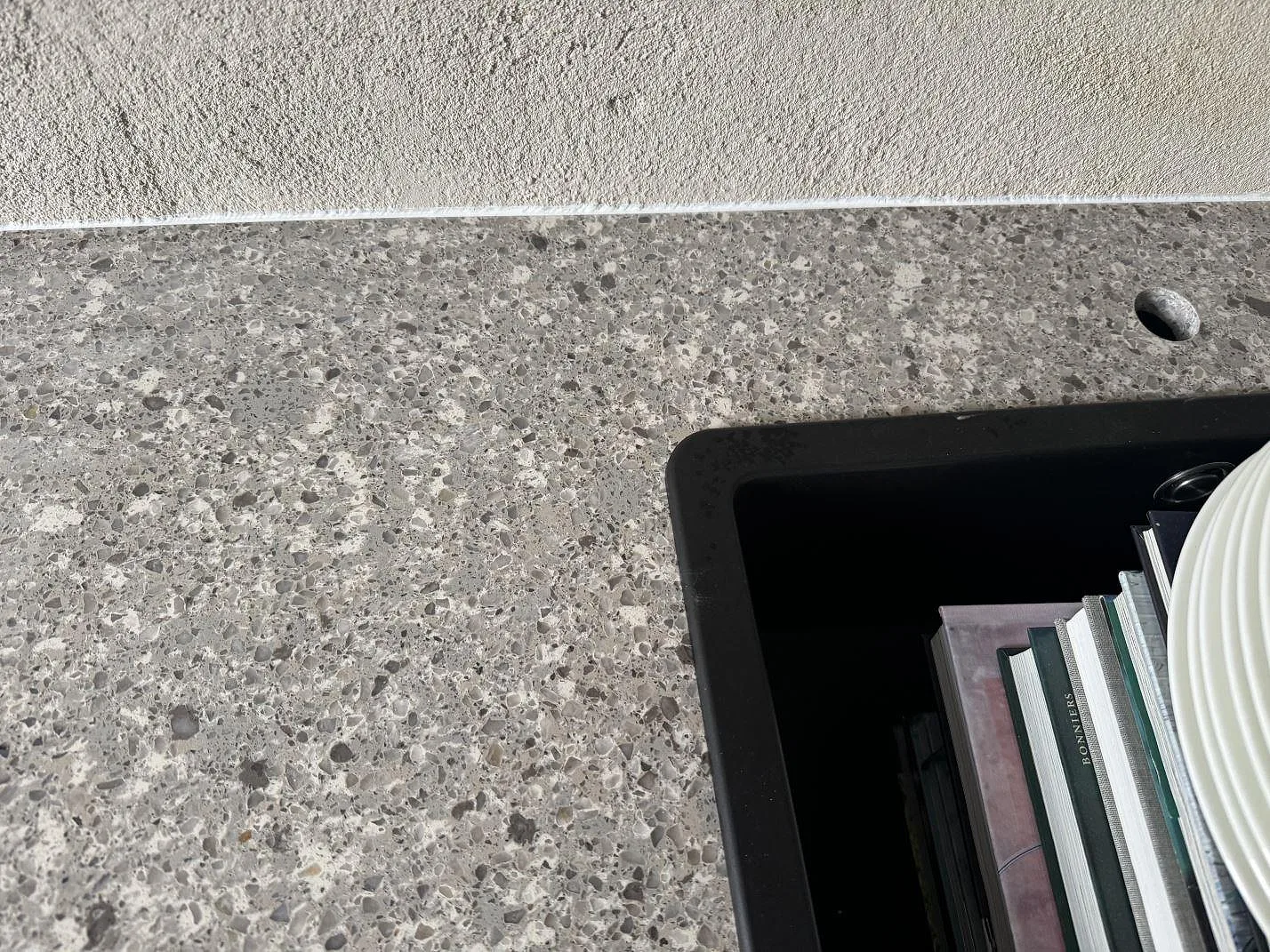 Närbild av gråvit Silestone Alpina White i polerad komposit med runt borrhål och svart insats i Limhamn.