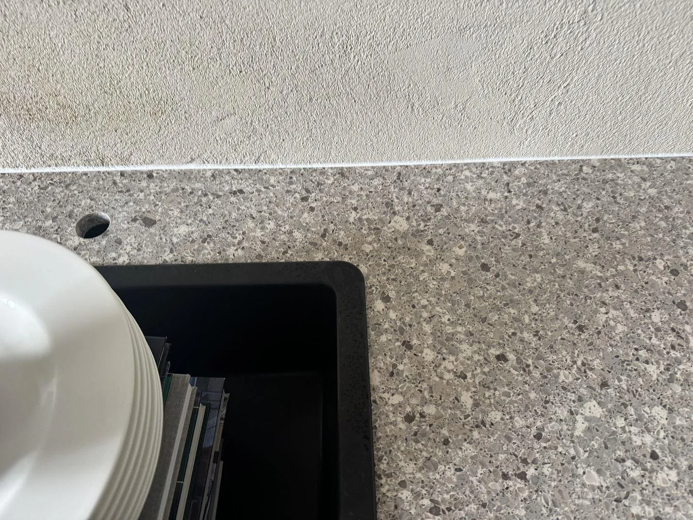 Detalj av polerad Silestone Alpina White runt svart infälld insats, med tät gråvit kvartskomposit i Limhamn.