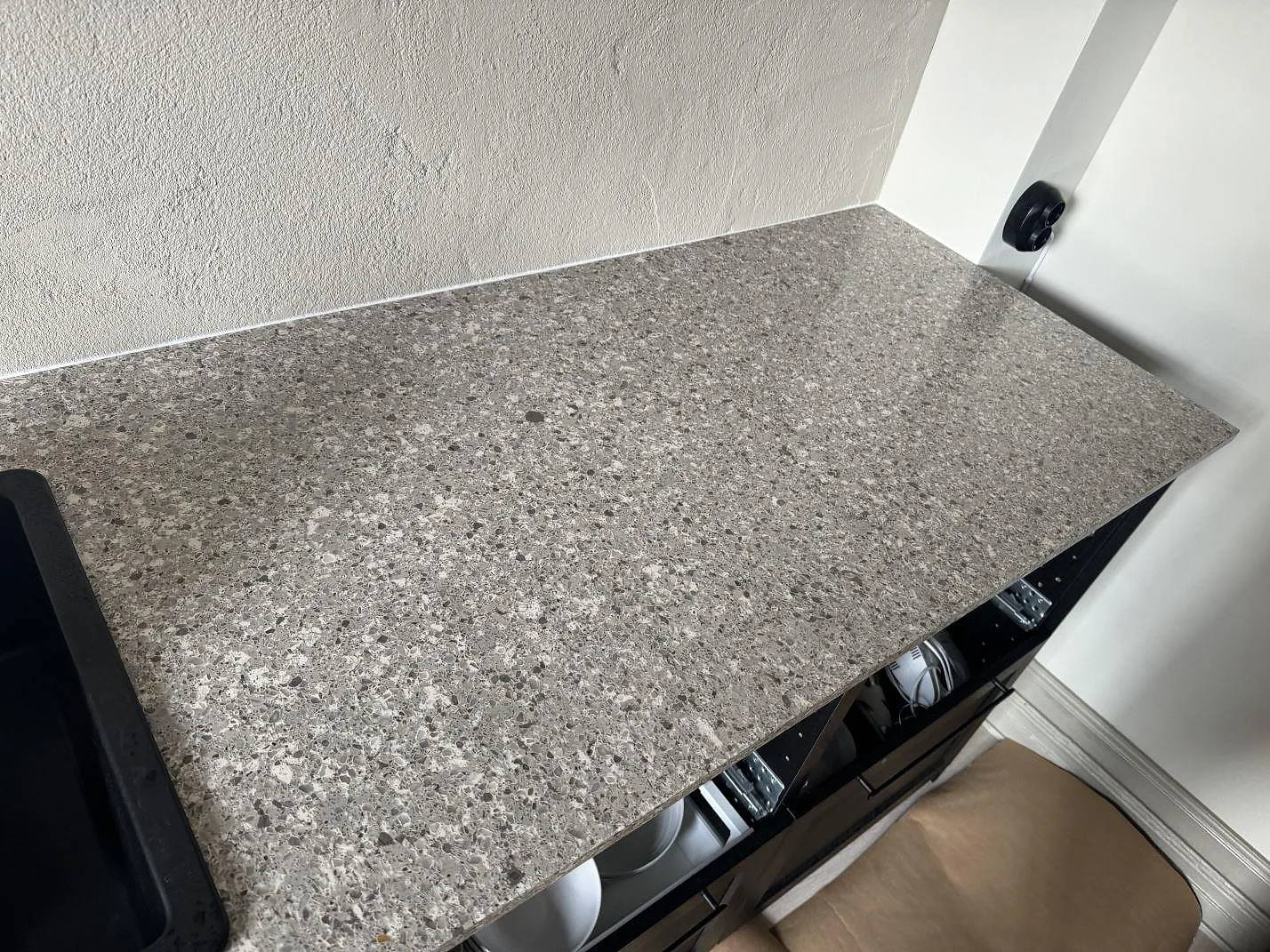 Närbild av polerad Silestone Alpina White som bänkskiva mot vägg, med grå och ljusa korn i ett kök i Limhamn.