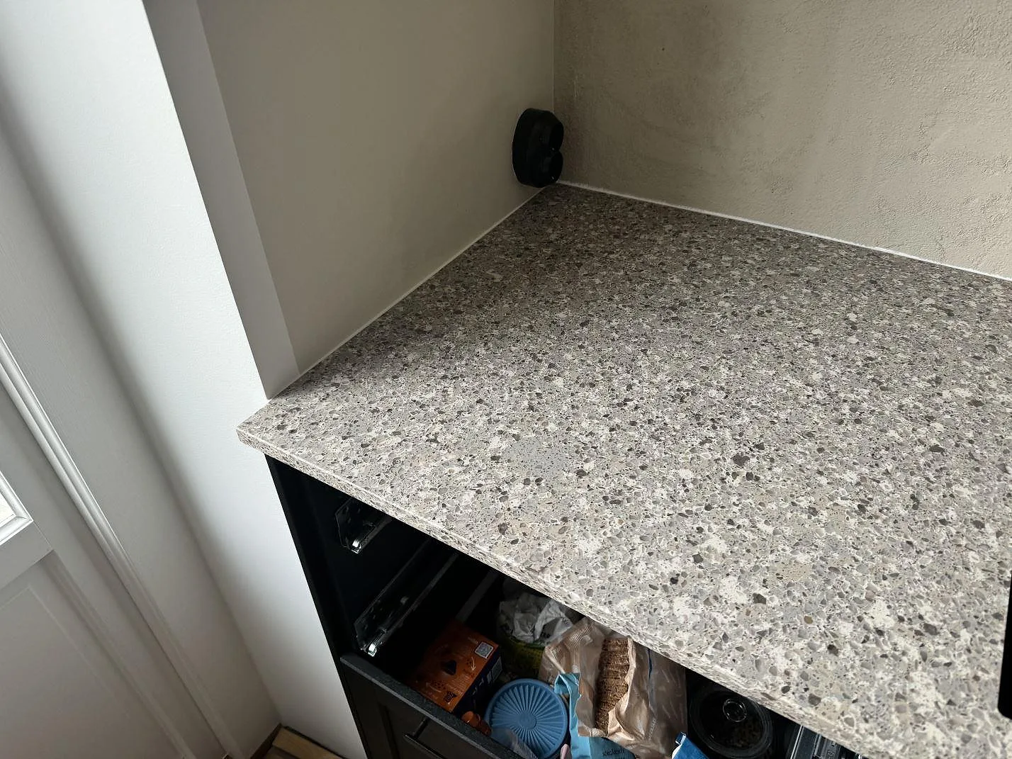 Polerad bänkskiva i Silestone Alpina White monterad vid fönster och vägg på svarta köksstommar i Limhamn.