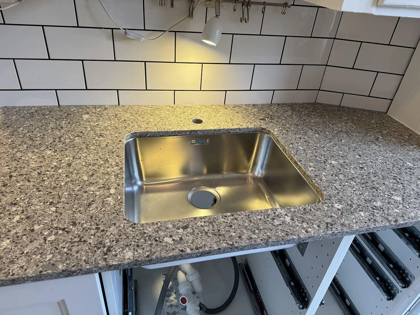 Underlimmad rostfri diskho i en bänkskiva av Silestone Alpina White, 20 mm Mocka, med vitt kakel i Malmö.