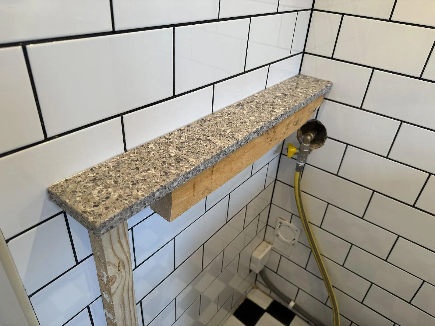 Liten vägghylla i Silestone Alpina White, 20 mm Mocka, monterad mot vitt kakel i Malmö.