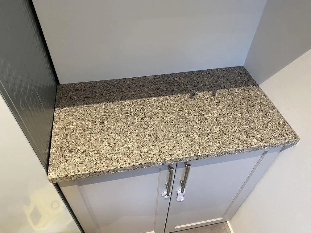 Kort bänkyta i polerad Silestone Alpina White ovanpå skåp, monterad i en passage i Malmö.