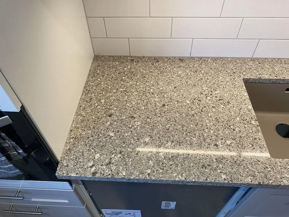 Ytdetalj av polerad Silestone Alpina White vid diskhon, med tät kompositstruktur och blank reflektion i Malmö.