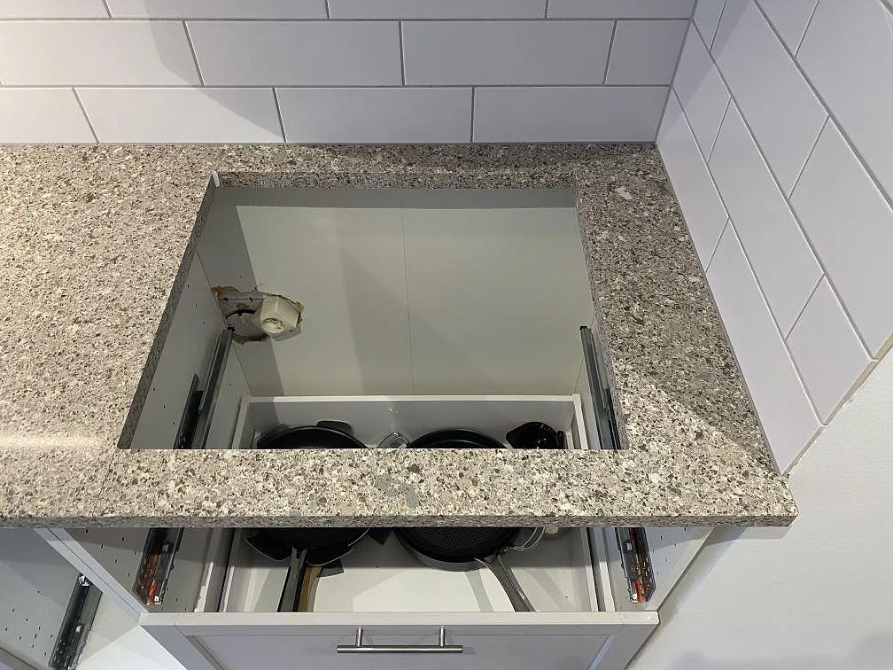 Hällöppning i köksbänkskiva av polerad Silestone Alpina White, monterad mot vitt kakel i Malmö.