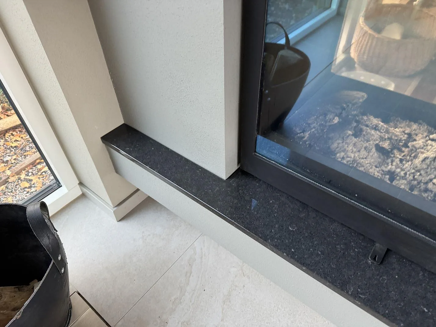 Smal eldstadsbänk i polerad Silestone Arden Blue med mörk komposityta intill glasad eldstad i Ängelholm.