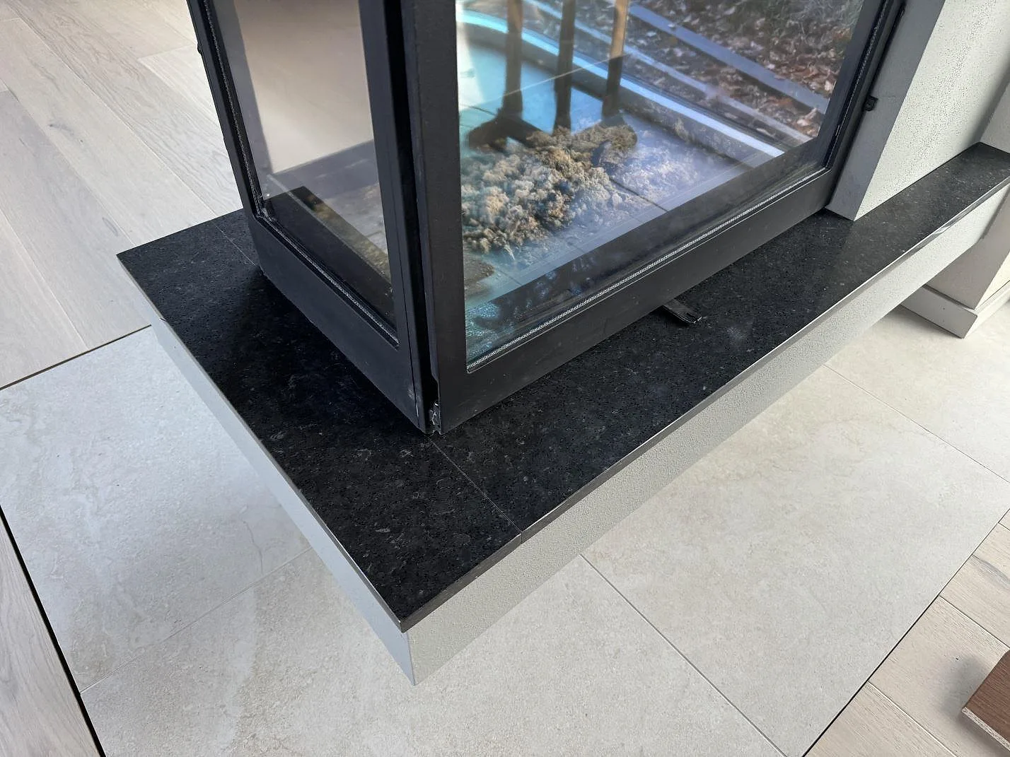 Polerad Silestone Arden Blue monterad som kompositskiva runt hörnet av eldstaden i Ängelholm.