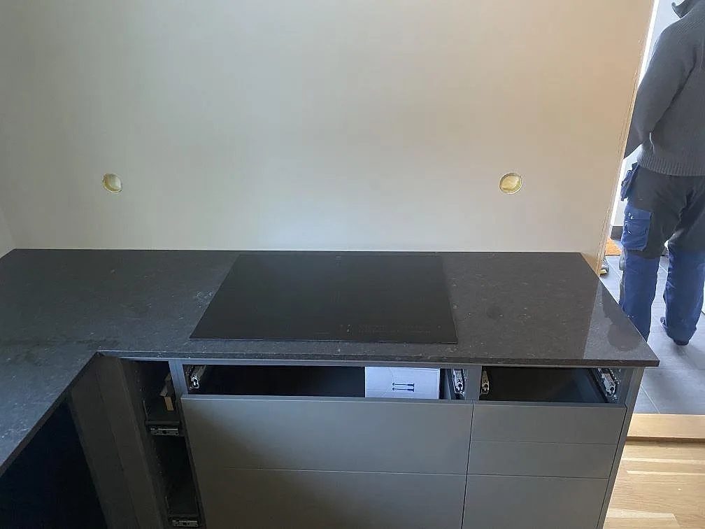 Köksbänkskiva i Silestone Arden Blue med monterad induktionshäll och mörka köksstommar under montering i Nättraby.