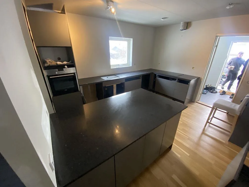 Köksbänkskiva i mörk Silestone Arden Blue, polerad, med köksö och väggbänkar i ett kök under montering i Nättraby.