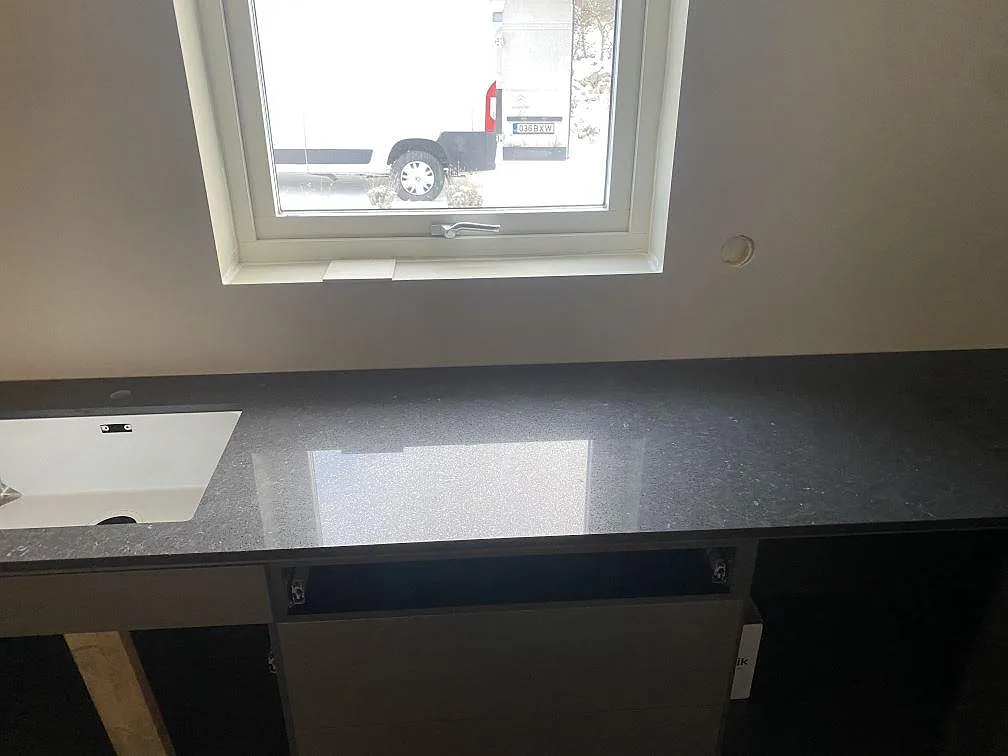 Bänkskiva i Silestone Arden Blue under fönster med diskho och polerad mörk yta i ett kök i Nättraby.