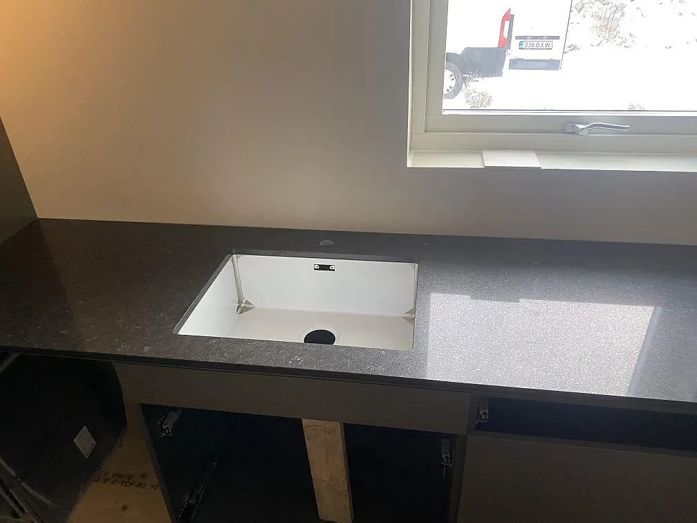 Diskho monterad i mörk polerad Silestone Arden Blue med fönster ovanför i ett kök under montering i Nättraby.