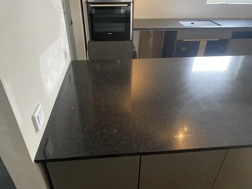 Polerad köksö i Silestone Arden Blue med synlig stenstruktur och bänkskiva med diskho i bakgrunden i Nättraby.
