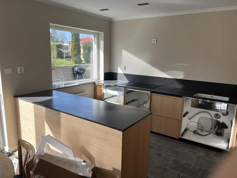 Köksbänkskiva i mörk Silestone Arden Blue, matt Mocka, med köksö, stänkskydd och svart häll i ett kök i Sävedalen.