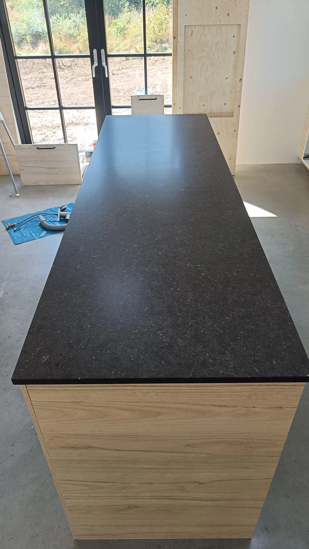 Lång köksö i Silestone Arden Blue, matt Mocka, med mörk kvartskomposit mot ljusa trästommar i Smedstorp.