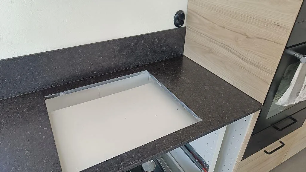 Detalj av hällurtag och stänkkant i Silestone Arden Blue, mörk matt kvartskomposit i ett kök i Smedstorp.