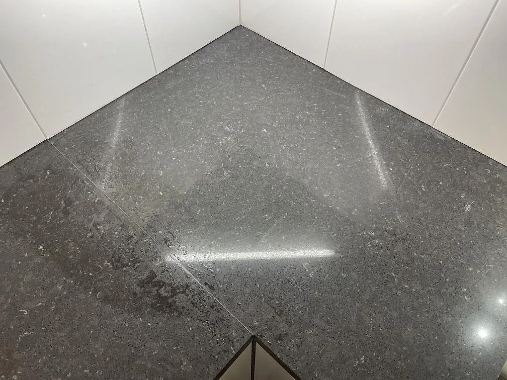 Närbild av hörn i polerad Silestone Arden Blue, blågrå kompositbänkskiva med finmönstrad yta i Stockholm.