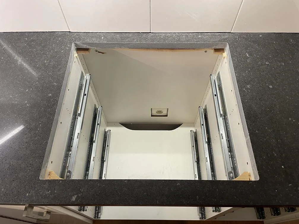 Detalj av urtagning i 30 mm polerad Silestone Arden Blue, mörk kompositbänkskiva under montering i ett kök i Stockholm.