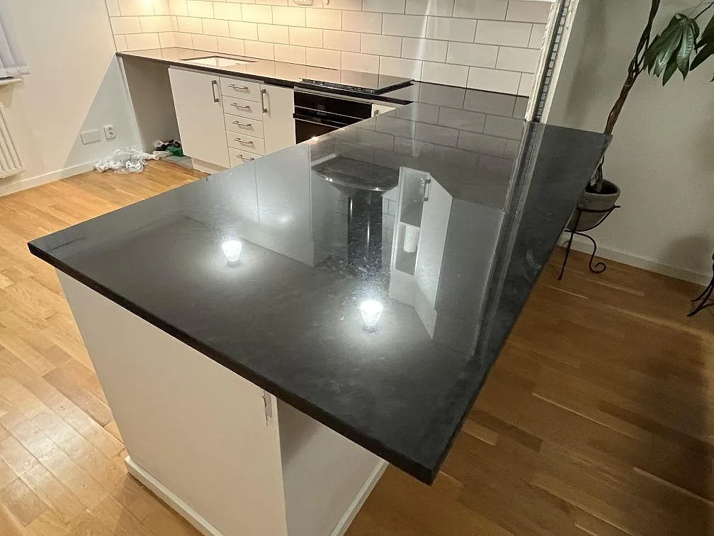 Polerad köksö i Silestone Arden Blue med mörk sten och vitt kakel i ett kök i Strängnäs.