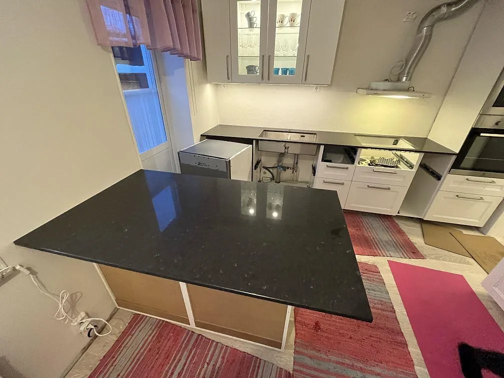 Köksbänkskiva och köksö i mörk Silestone Arden Blue, polerad kvartskomposit, i ett kök under montering i Strängnäs.