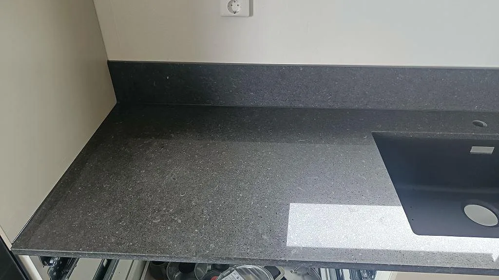 Detalj av polerad Silestone Arden Blue med uppvikt stänkkant och underlimmad kompositho i ett kök i Torslanda.