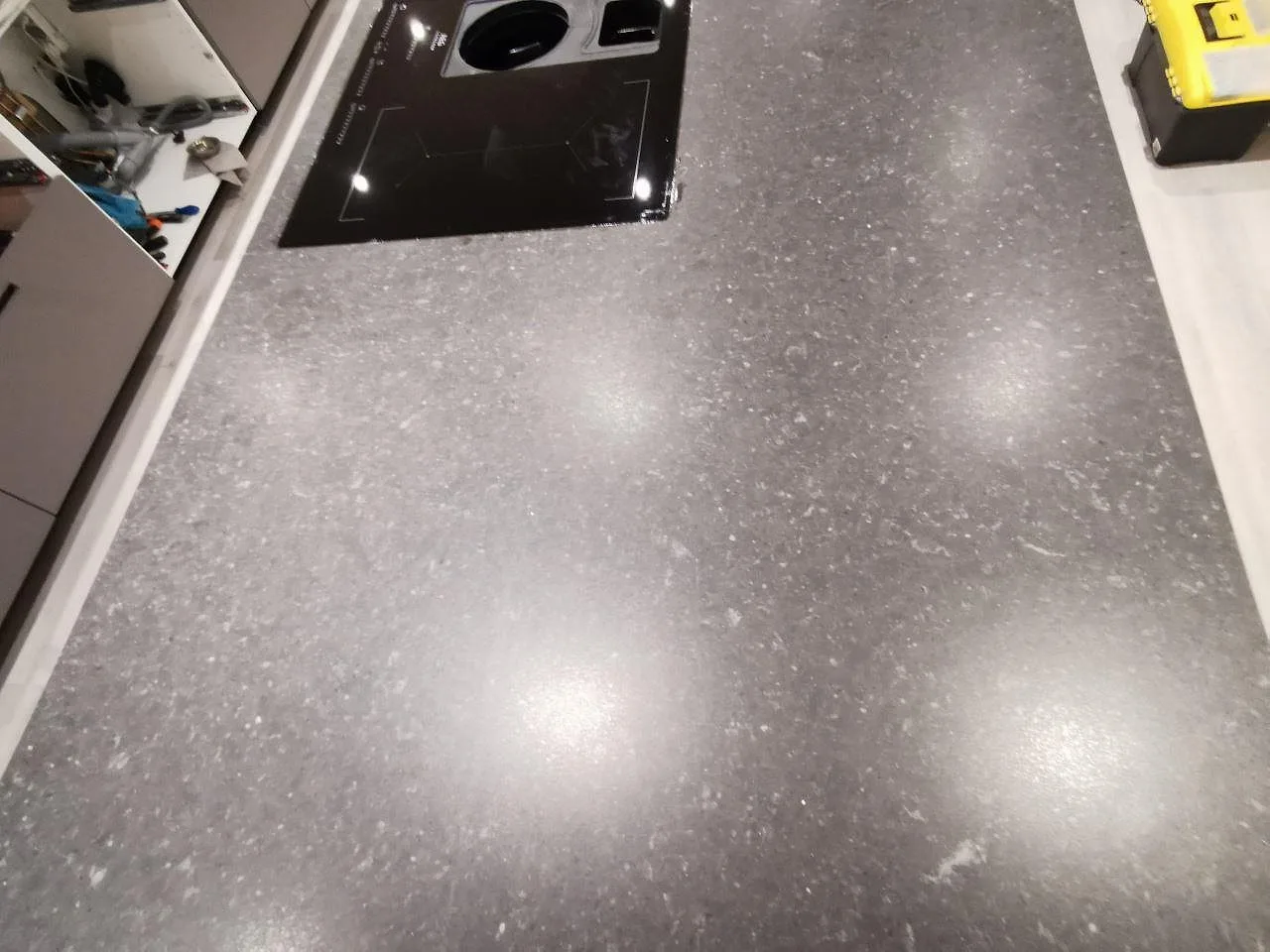 Köksbänk i Silestone Arden Blue med urtag för planmonterad häll, matt mörkgrå kvartskomposit med ljus prickning, i ett kök under montering i Varberg.