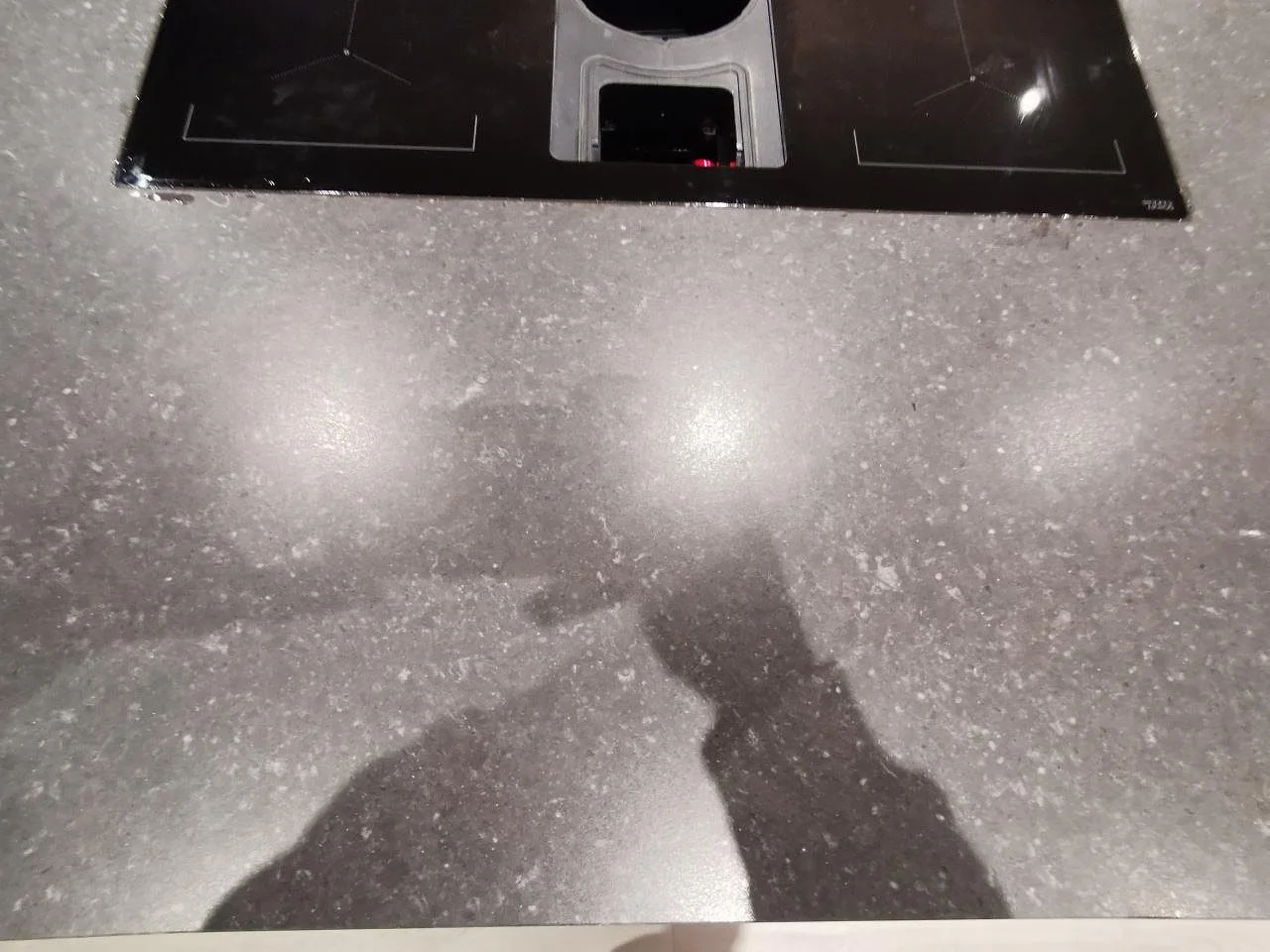 Planmonterad induktionshäll med nedfälld fläkt i en köksö av Silestone Arden Blue, mörk matt kvartskomposit, i ett kök i Varberg.