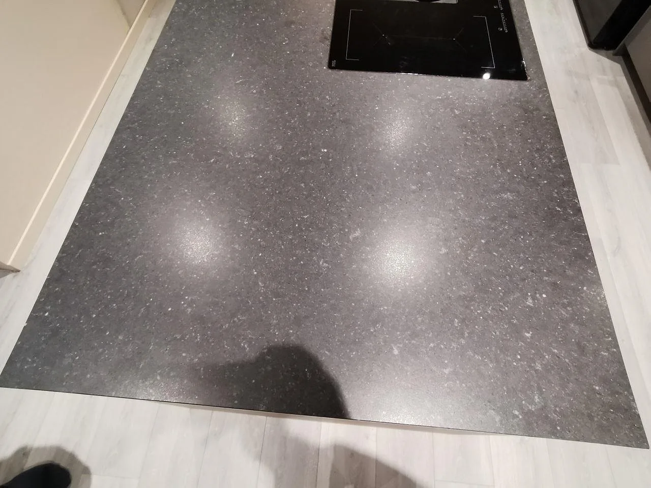 Köksö i Silestone Arden Blue med planmonterad induktionshäll och integrerad fläkt, matt blågrå kvartskomposit med ljus prickning, i ett kök i Varberg.