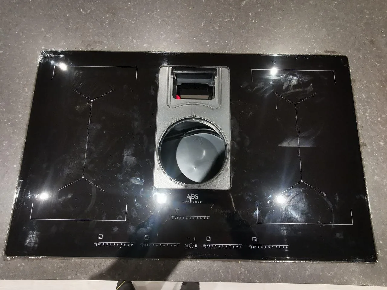 Detalj av planmonterad AEG induktionshäll infälld i nivå med köksön i Silestone Arden Blue, matt blågrå kvartskomposit, i Varberg.