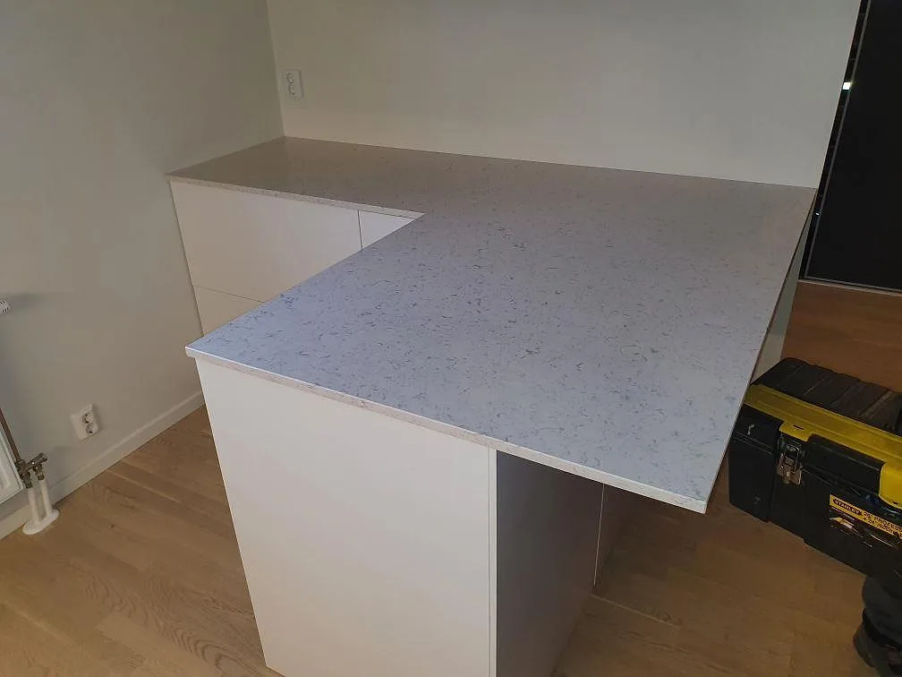 Köksbänkskiva i ljus Silestone Bianco River, polerad komposit, monterad på vita köksstommar i Saltsjö Boo.