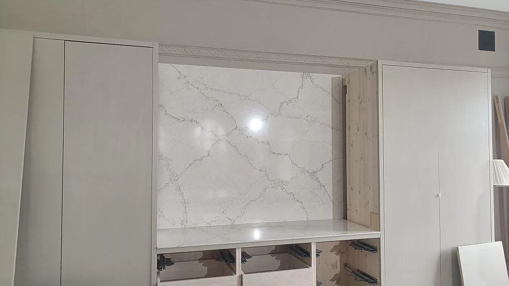 Rak vy mot matchande väggpanel i polerad Silestone Blanc Elysee över bänkskiva och öppna köksstommar i Allerum.