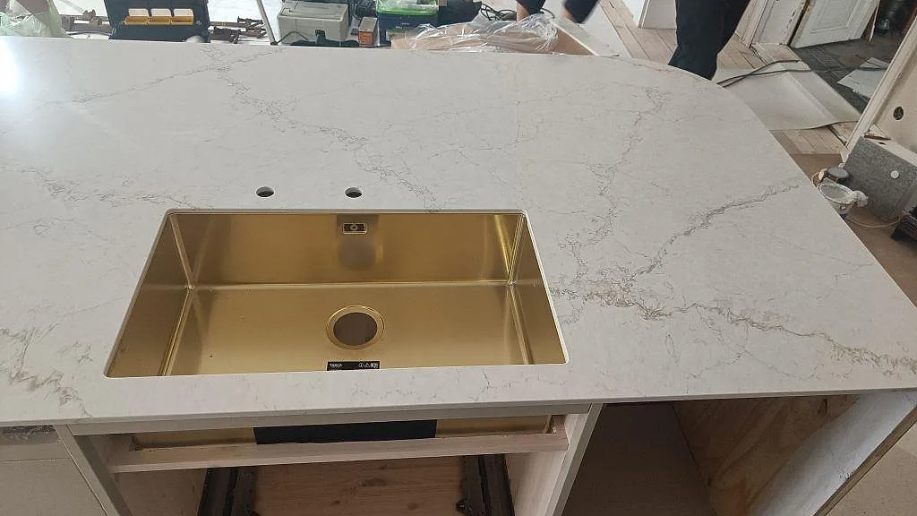 Närbild på diskho i köksbänkskiva av polerad Silestone Blanc Elysee, med vit kompositsten och grå marmorering i Allerum.