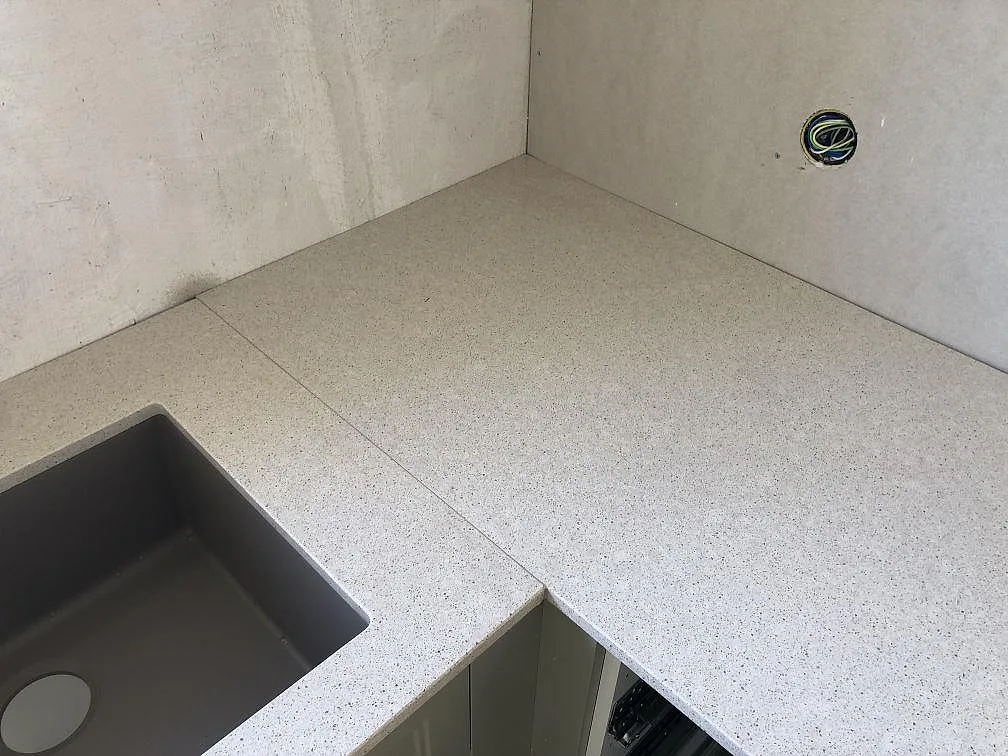 Hörnparti i Silestone Blanco City med underlimmad grå kompositdiskho i ett kök i Ängelholm.