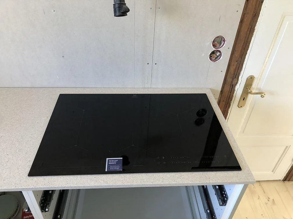 Infälld induktionshäll i en köksbänkskiva av vit Silestone Blanco City i Ängelholm.