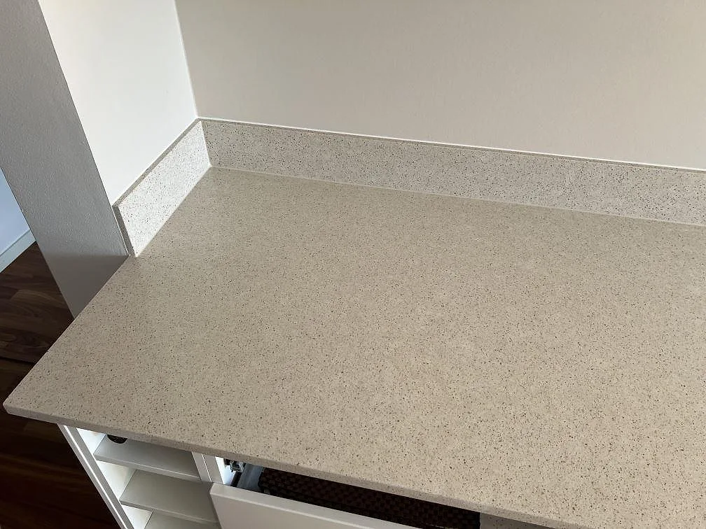 Närbild på greige Silestone Blanco City kompositbänkskiva, polerad, med matchande stänkkant i Bjärred.