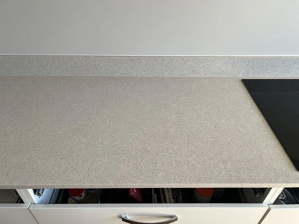Polerad Silestone Blanco City bänkskiva i komposit med svart hällkant och stänkkant i ett vitt kök i Bjärred.
