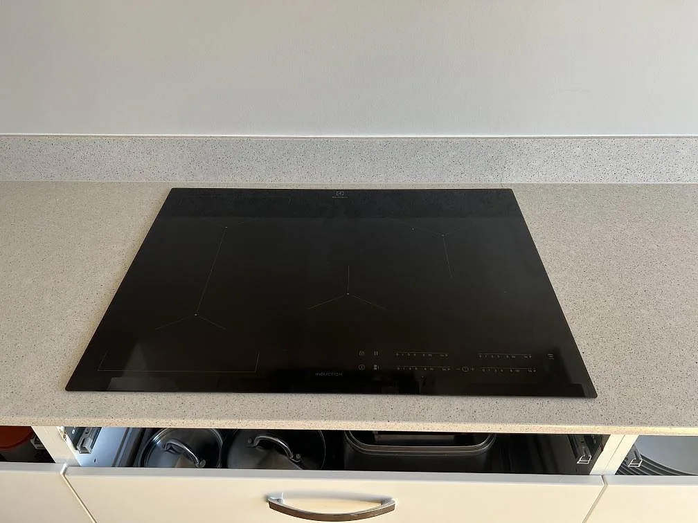Svart induktionshäll i polerad Silestone Blanco City kompositbänkskiva med uppvikt stänkkant i Bjärred.